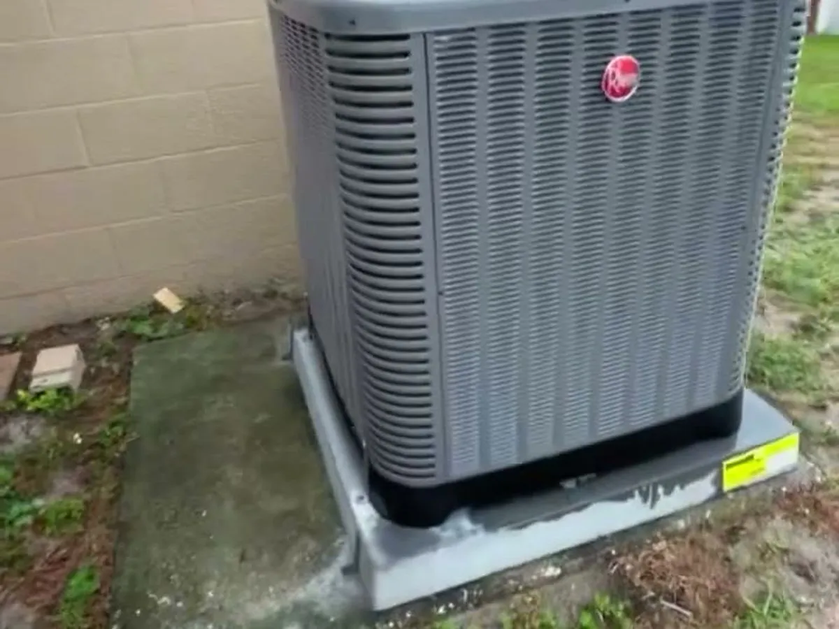 A gray Rheem outdoor condenser on a concrete pad beside a Tampa home